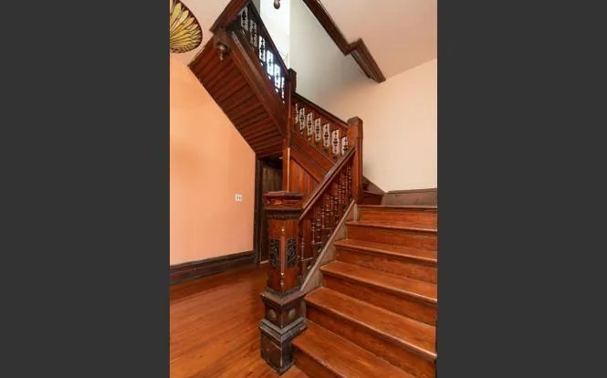 Restored original Victorian-era staircase with carved newel post and detailed balusters